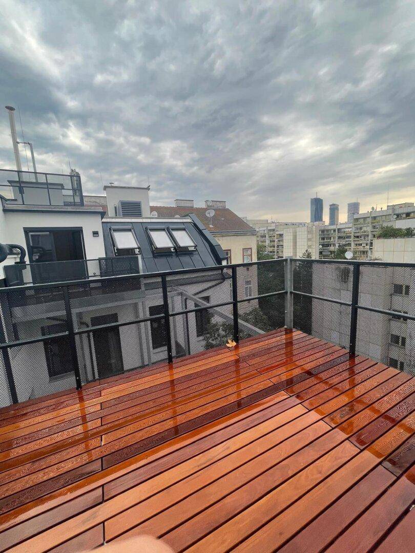 Große Holzterrasse mit Blick auf die Dächer der Stadt an einem bewölkten Tag.