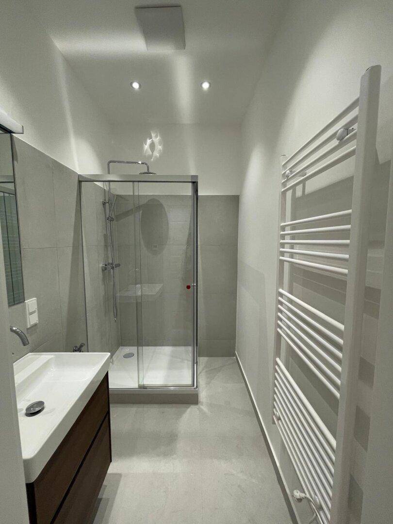 Modernes Badezimmer mit Duschkabine, Einzelwaschbecken und beheiztem Handtuchhalter.