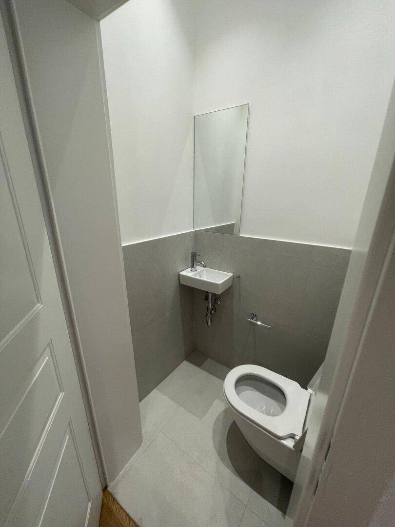 Kleines Gäste-WC mit wandhängender Toilette, kleinem Waschbecken und modernem Design.