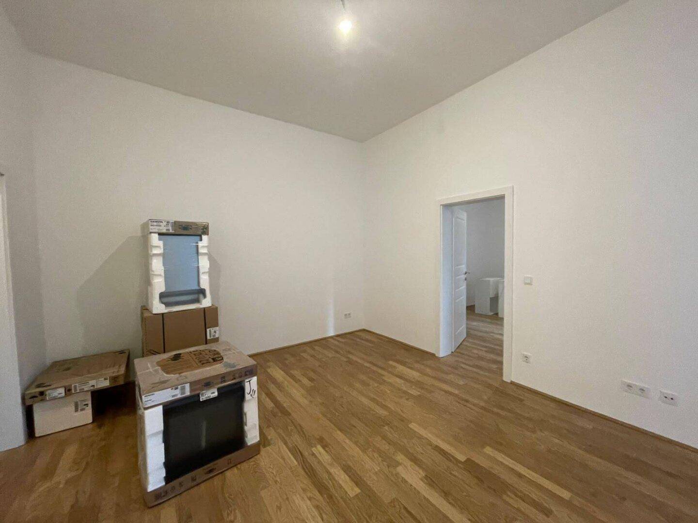Geräumiges Zimmer mit Parkettboden und weißer Tür, ideal für individuelle Gestaltung.