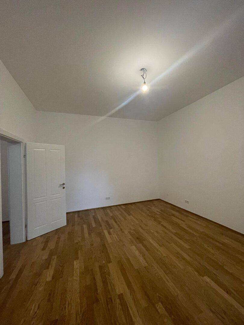 Geräumiges Zimmer mit Parkettboden und weißer Tür, ideal für individuelle Gestaltung.