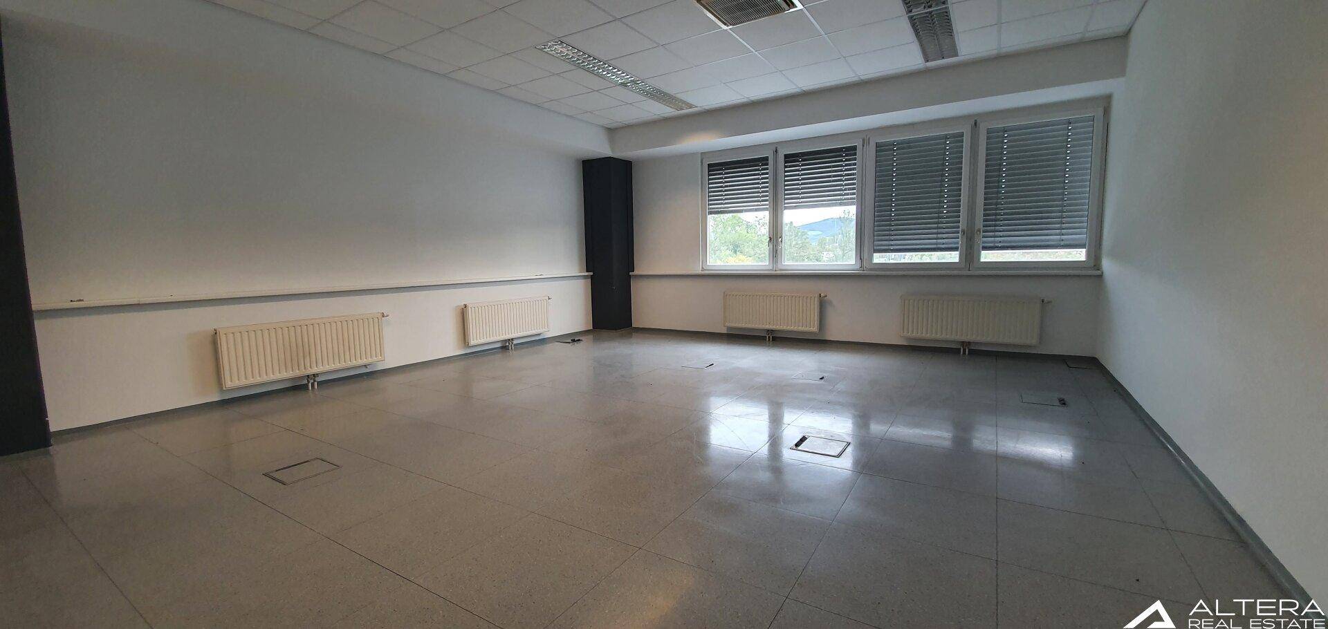 Geräumiges, leeres Büro mit großen Fenstern, Heizkörpern und Fliesenboden, bereit zur individuellen Gestaltung.
