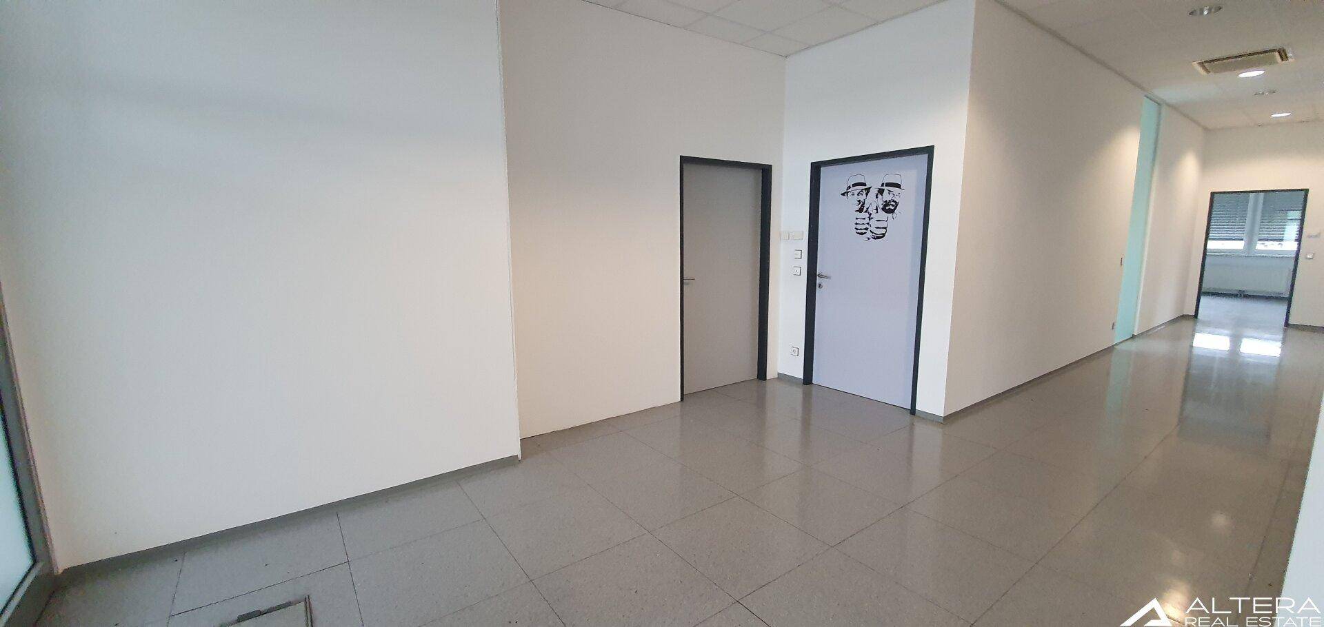 Heller Flur mit mehreren Türen und Fliesenboden, der einen Zugang zu verschiedenen Büroräumen bietet.