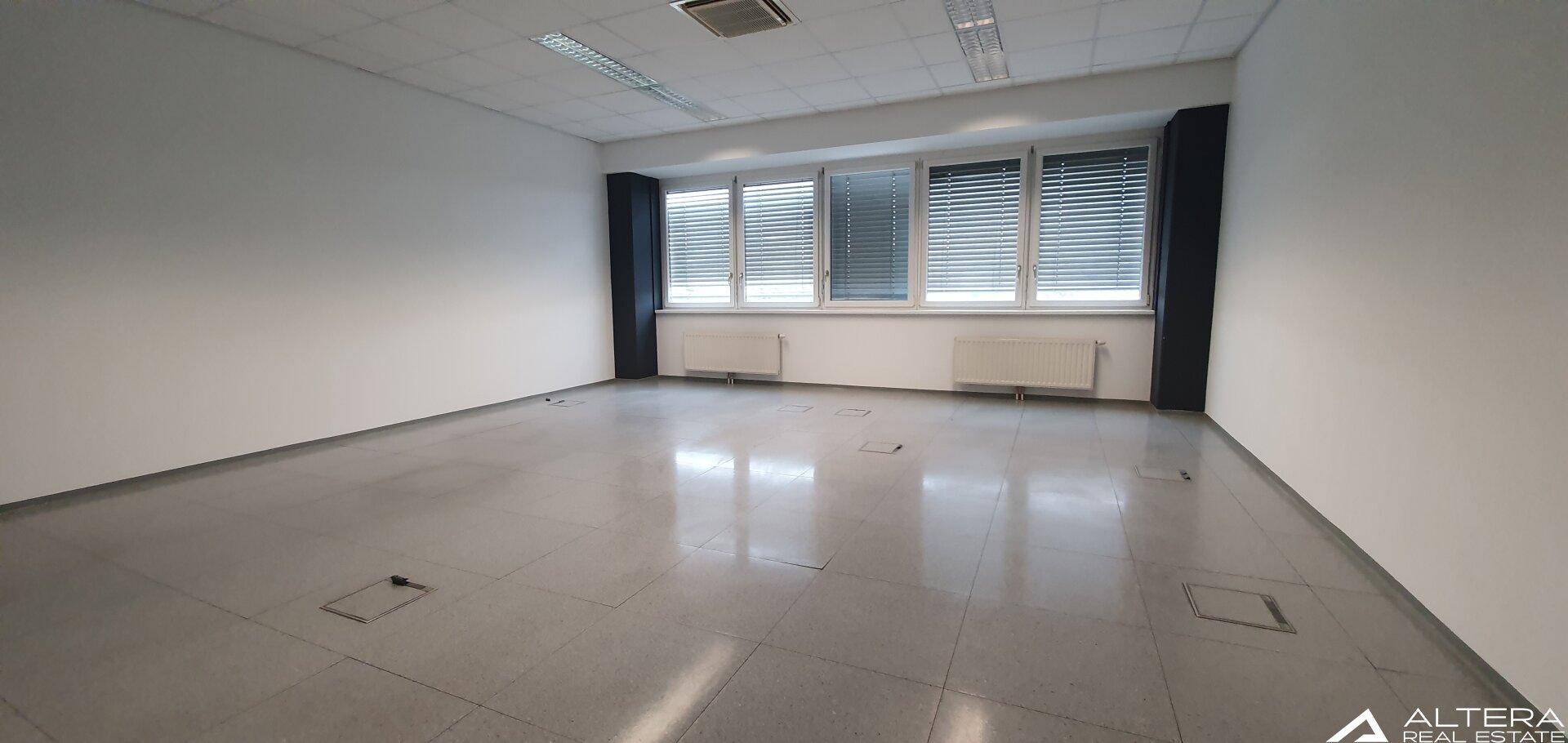 Helles Büro mit großen Fenstern, Jalousien und einem praktischen Fliesenboden, ideal für Arbeitsbereiche.