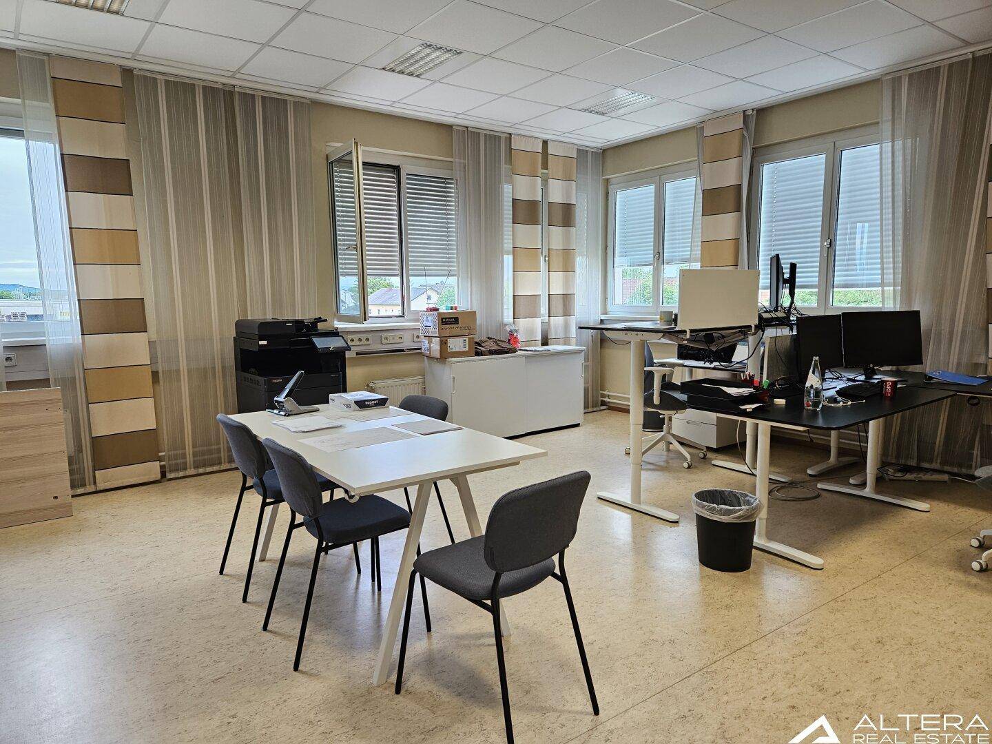 Geräumiges Büro mit Besprechungstisch, mehreren Arbeitsplätzen und großen Fenstern mit Ausblick.