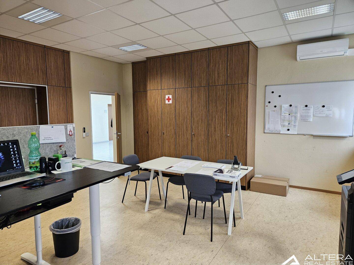 Büro- oder Besprechungsraum mit Holzwandverkleidung, Whiteboard und Klimaanlage.