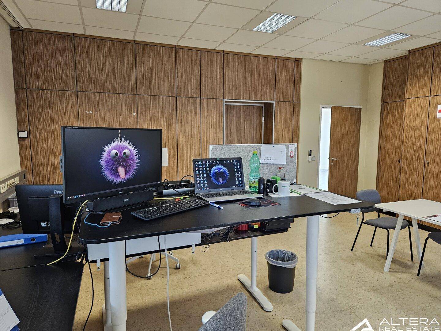 Büro mit Holzvertäfelung, mehreren Arbeitsplätzen und einem Stehschreibtisch.