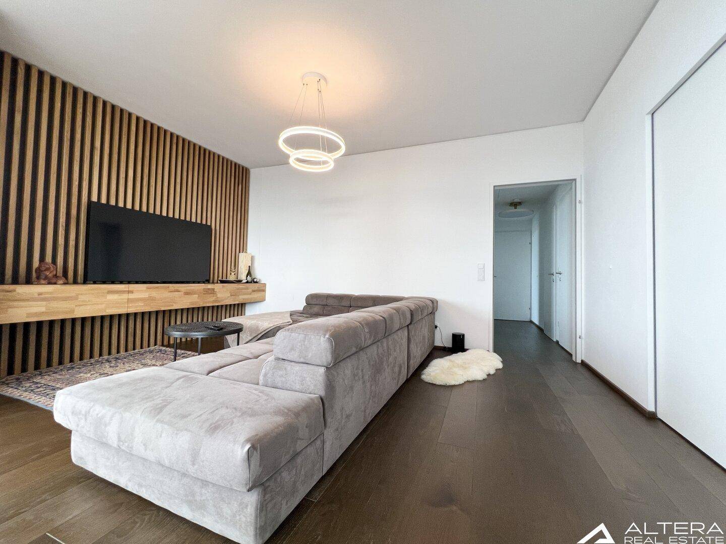 Moderner Wohnbereich mit großem Ecksofa und stilvoller Holzlamellenwand.