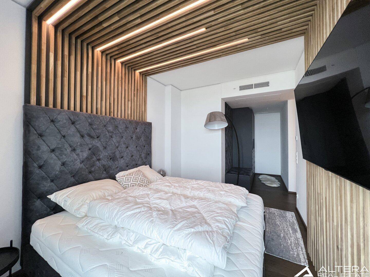 Stilvolles Schlafzimmer mit integrierter Holzlamellen-Beleuchtung und modernem Bett.