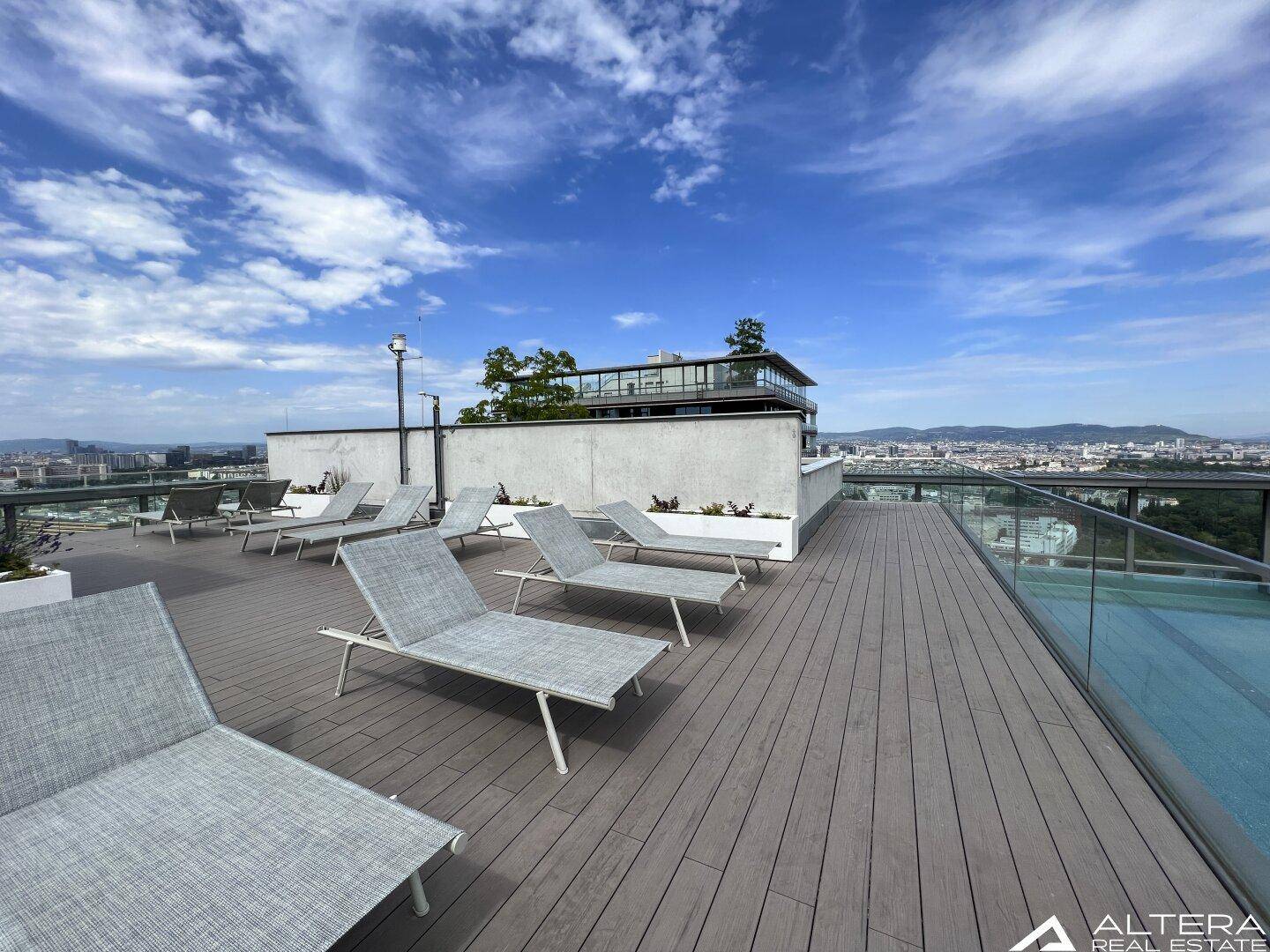 Entspannungsbereich auf der Dachterrasse mit Liegestühlen und Panoramablick.