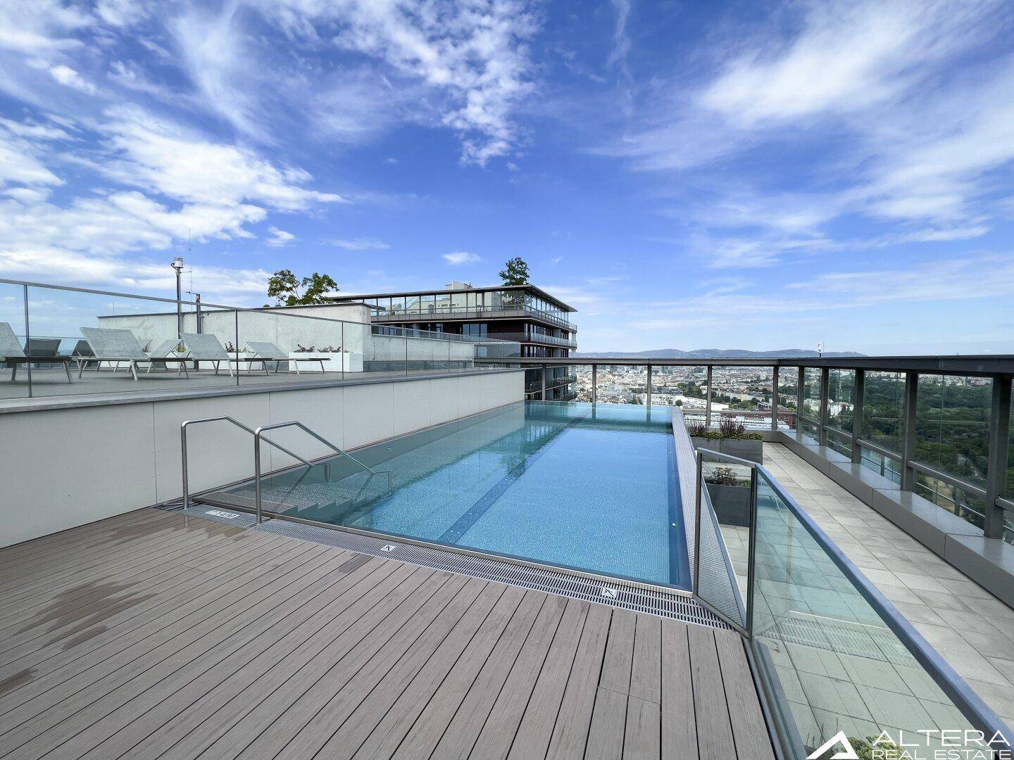 Dachpool mit Holzdeck und weitem Blick auf die Stadtlandschaft und den Horizont.