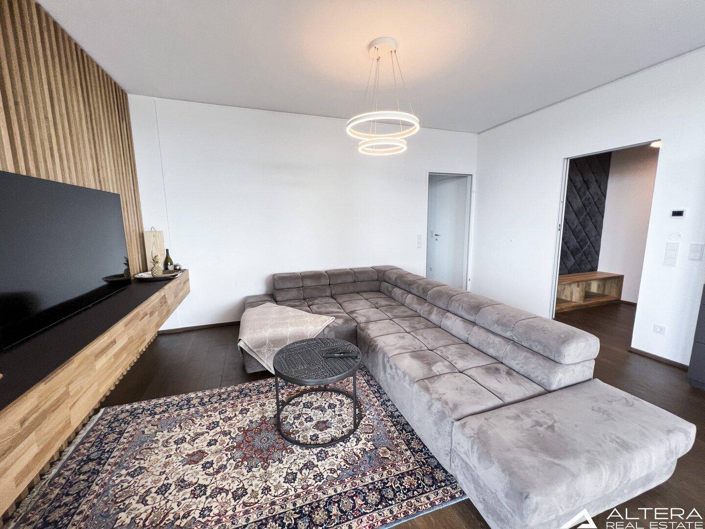 Gemütlicher Wohnbereich mit großem Ecksofa und dekorativer Holzlamellenwand.