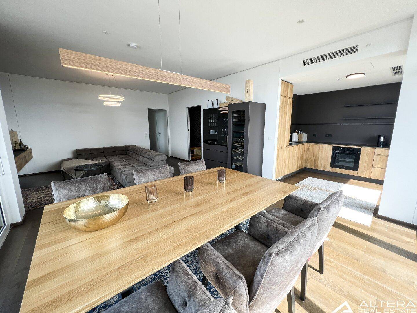 Geräumiger Wohn-Essbereich mit integrierter Küche, Holzboden und moderner Beleuchtung.