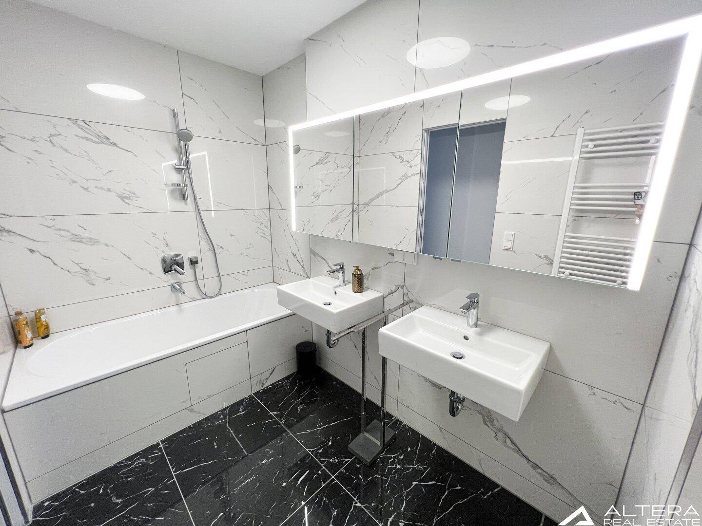 Modernes Badezimmer mit Badewanne, Doppelwaschbecken und eleganten Marmorfliesen.