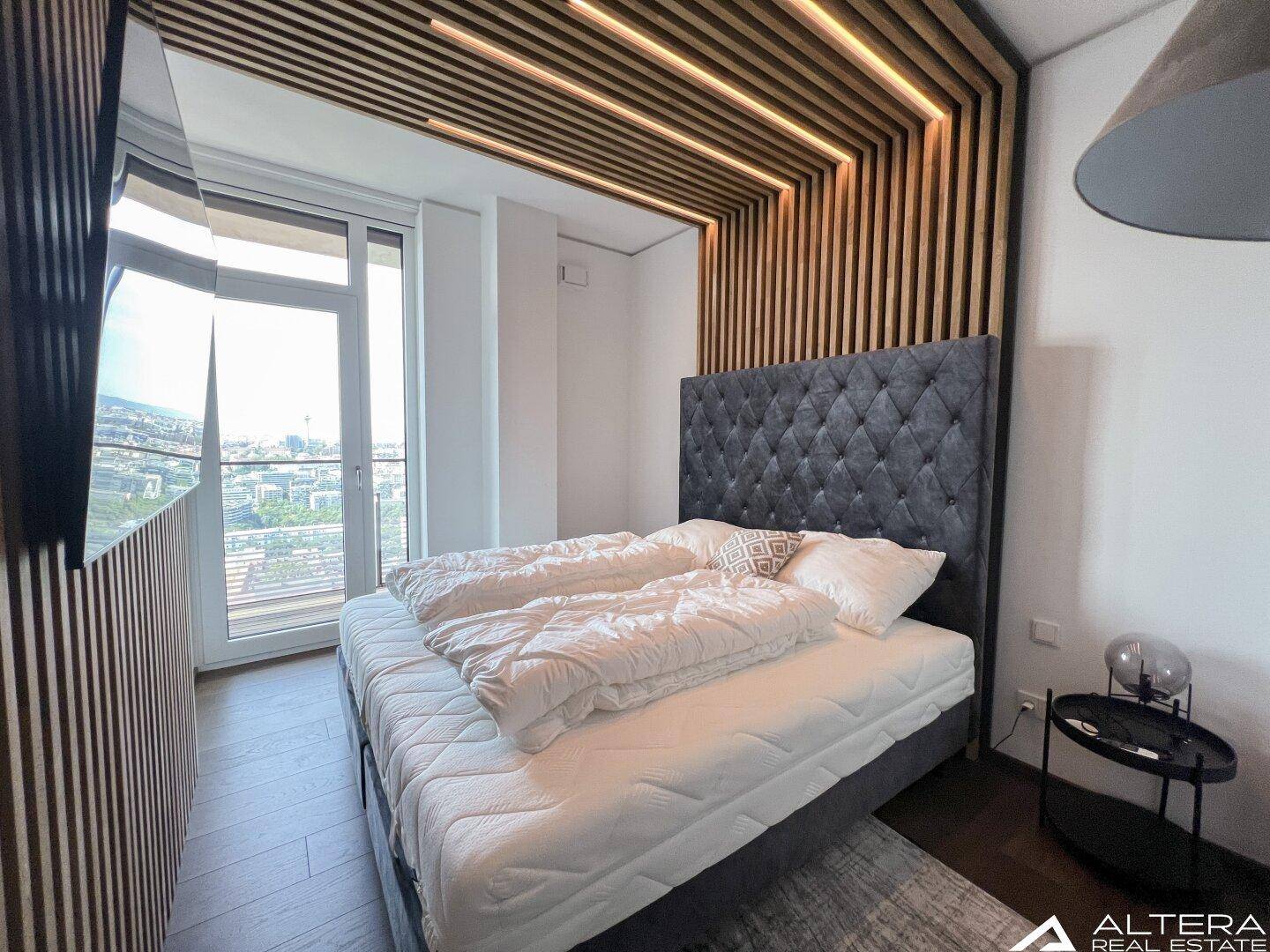 Schlafzimmer mit einzigartiger Holzlamellen-Decken- und Wandgestaltung und Balkonzugang.