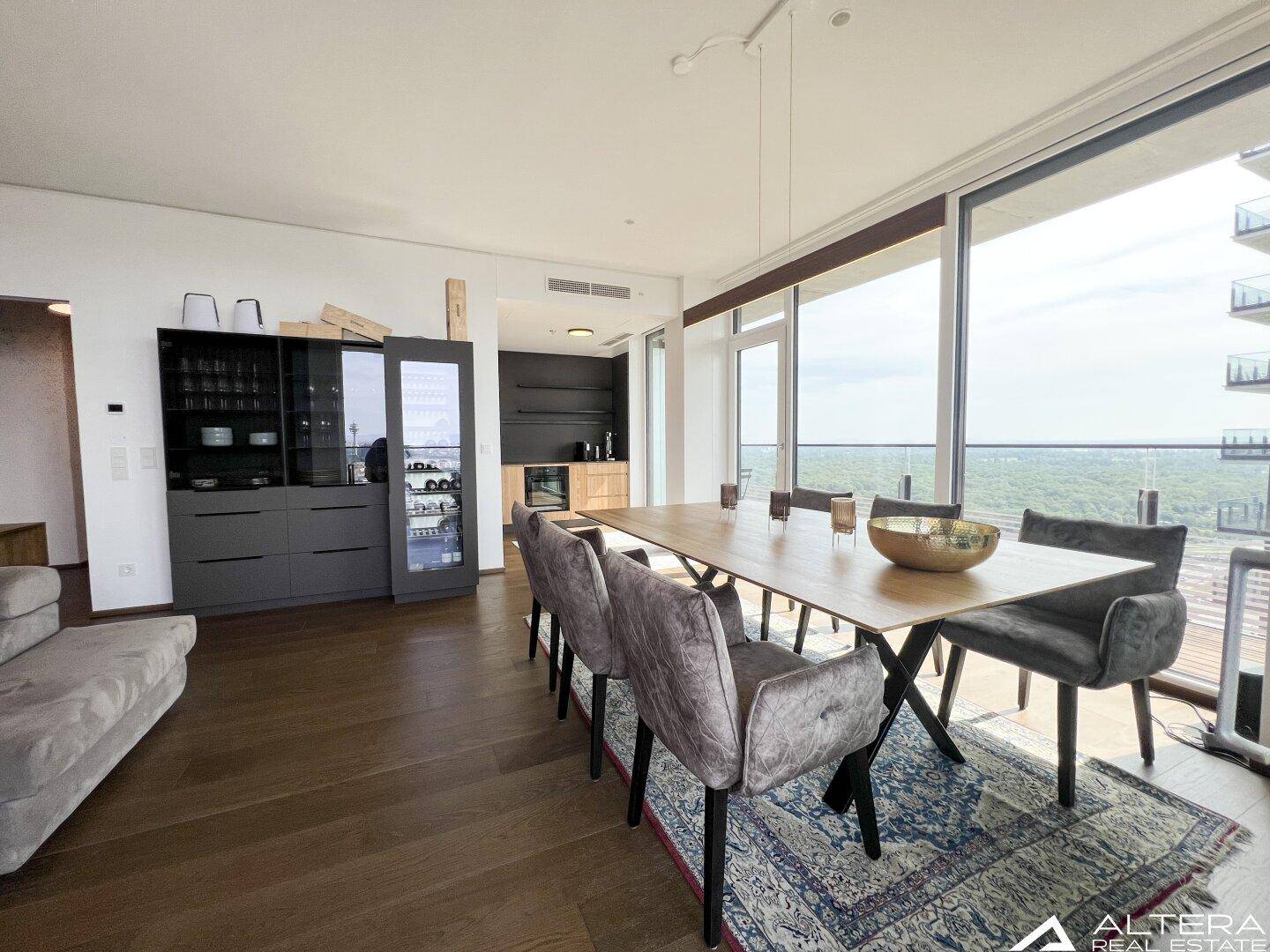 Heller, offener Wohn-Essbereich mit Holzboden, modernen Möbeln und Panoramablick auf die Stadt.