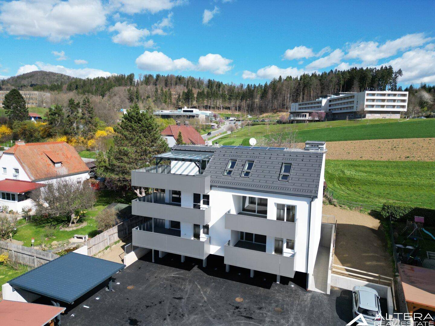 Drohnenaufnahme des Neubaus mit mehreren Balkonen und einer großzügigen Dachterrasse.