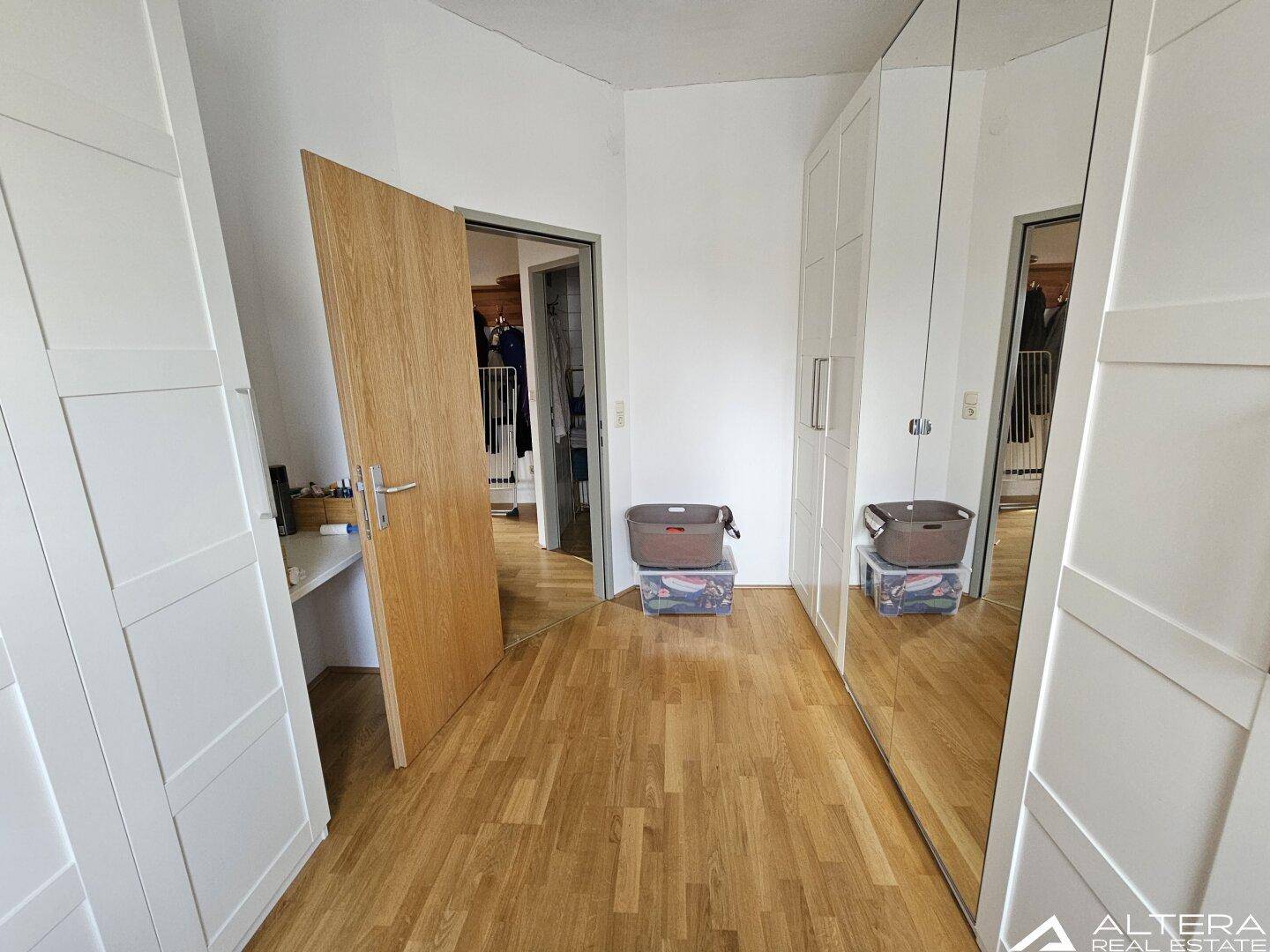 Heller Flur mit Holzparkettboden und großen Spiegelschränken, die viel Stauraum bieten.