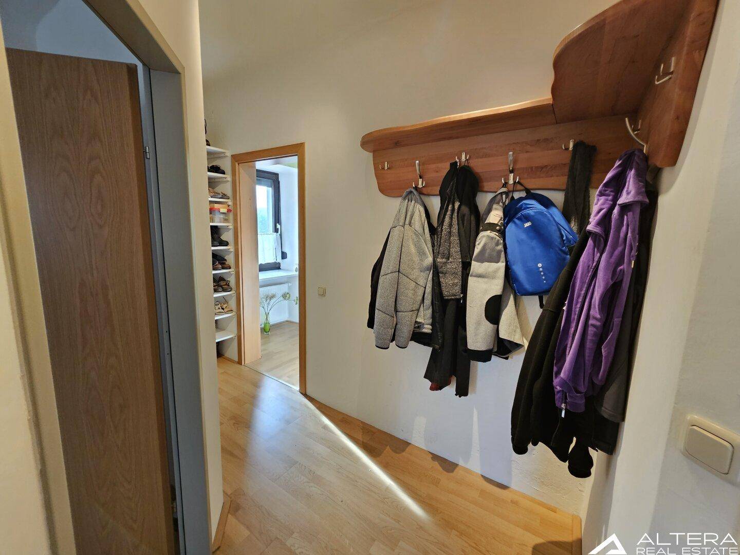 Eingangsbereich mit Holzparkettboden und einer Garderobe, die viel Platz für Kleidung bietet.