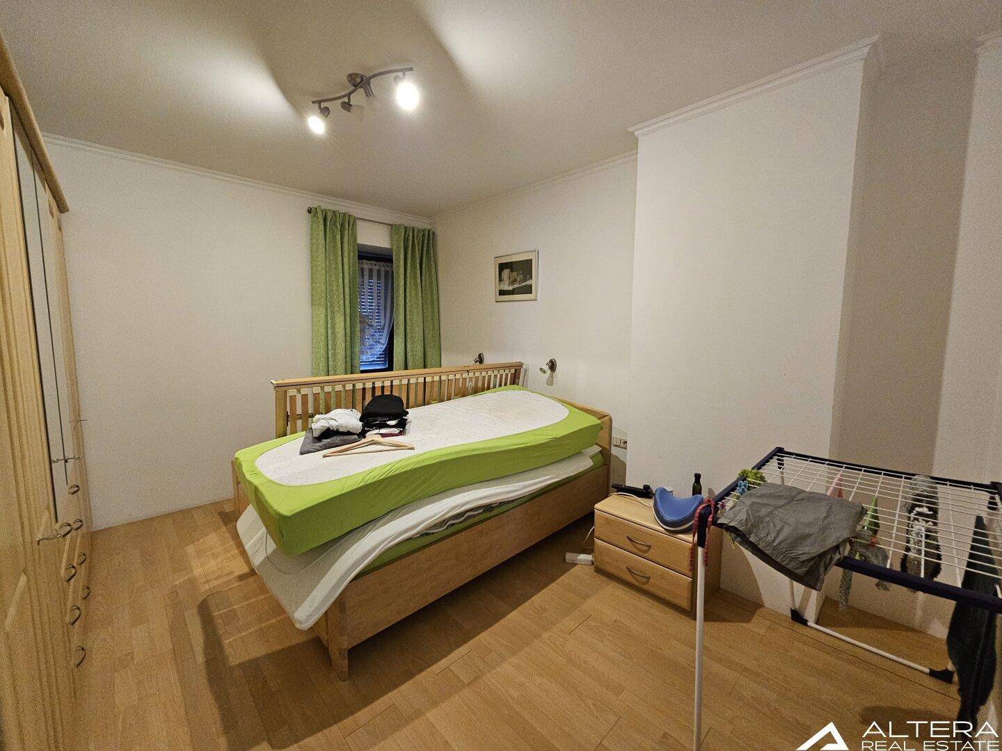 Schlafzimmer mit Holzparkettboden, einem Bett und einem Kleiderschrank, in hellem Ambiente.