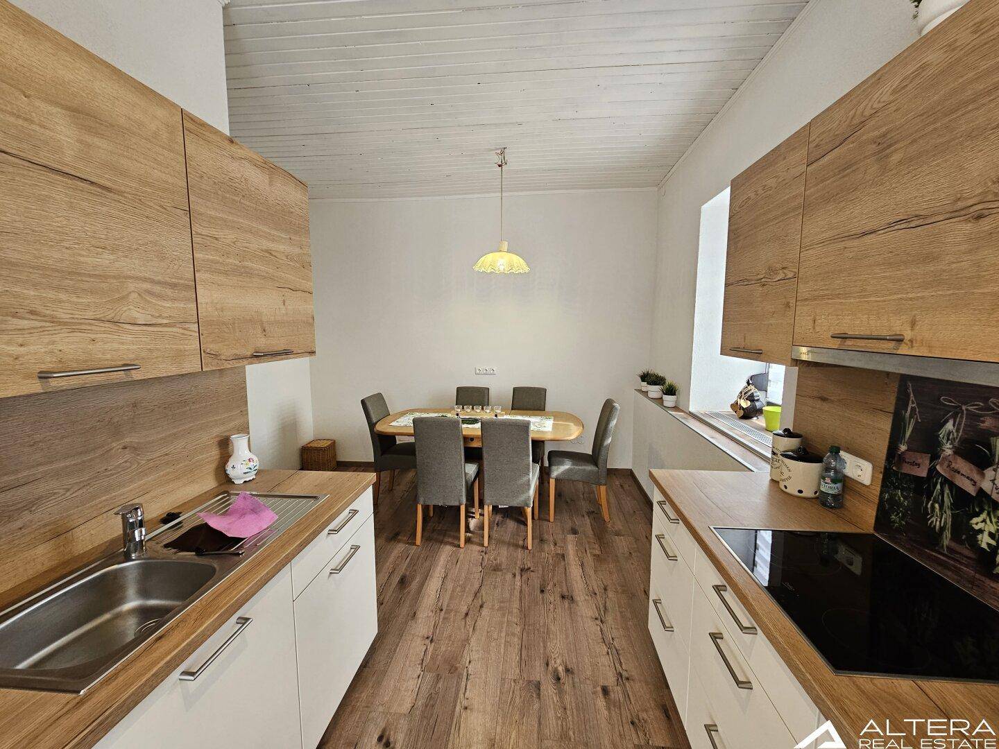 Moderne Küche mit Holzarbeitsplatten, weißen Unterschränken und einem Essbereich.