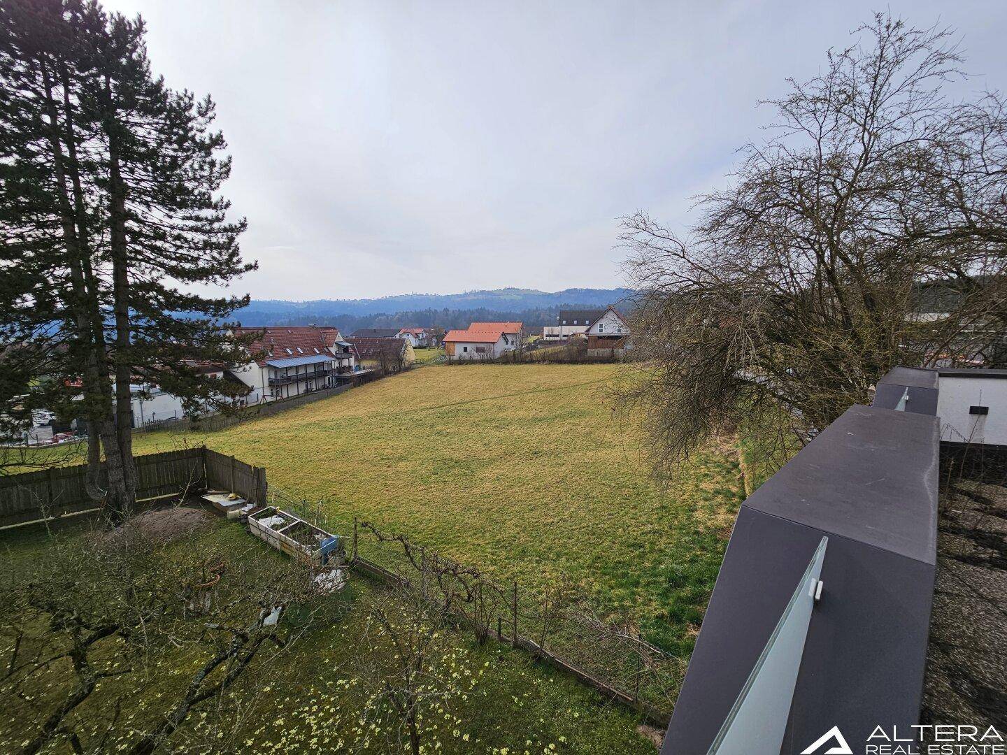 Weitläufiger Blick über grüne Felder und die umliegende Landschaft mit vereinzelten Häusern.
