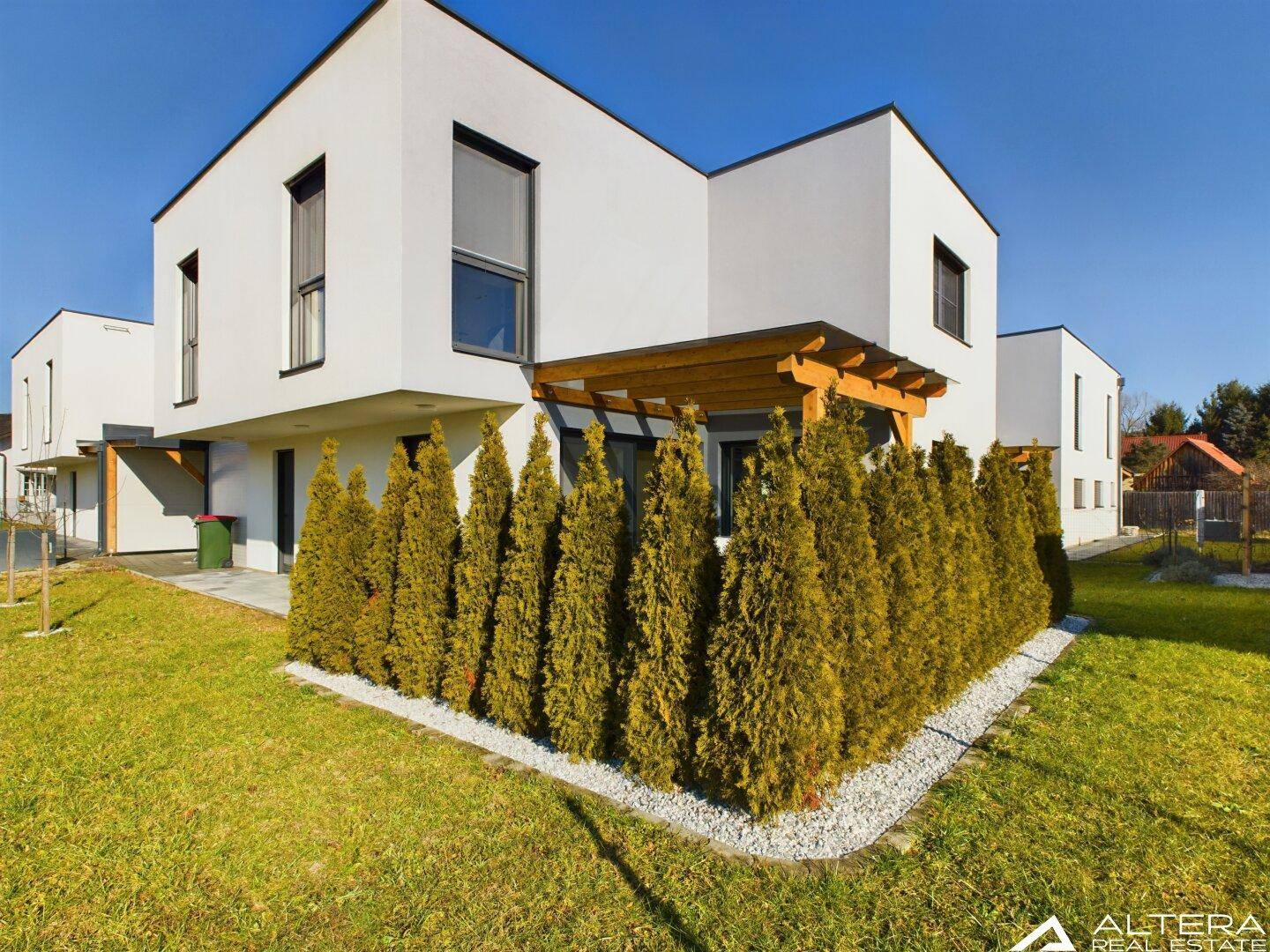 Seitenansicht eines modernen Hauses mit hoher Hecke, die Privatsphäre im Gartenbereich bietet.