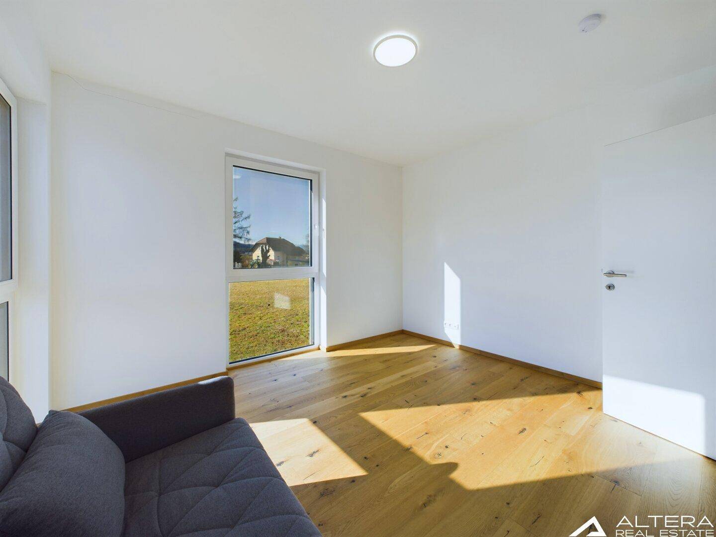 Geräumiges Schlafzimmer mit Holzboden, viel Tageslicht und einem weiten Blick ins Grüne.
