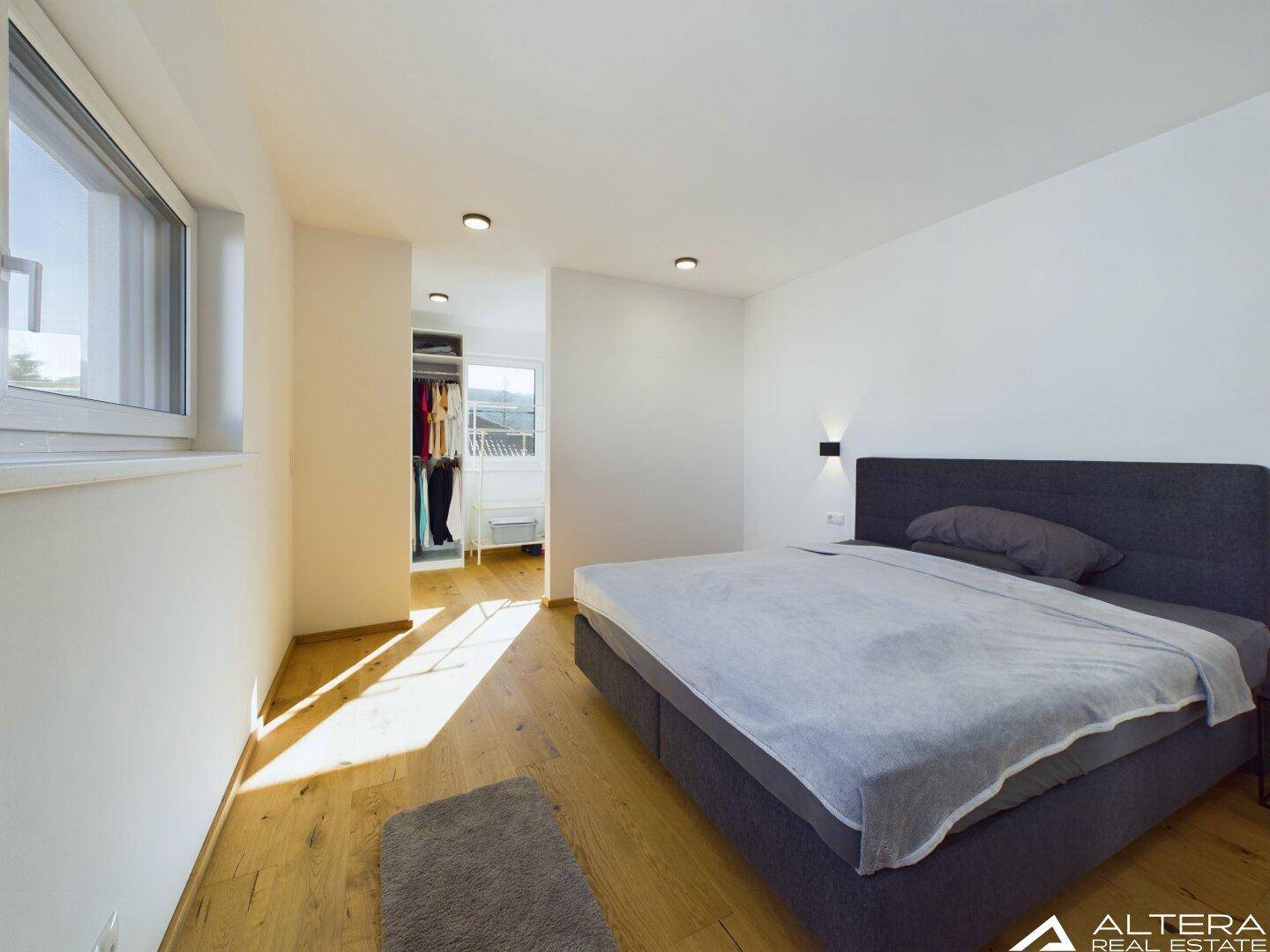 Helles Schlafzimmer mit Holzboden und direktem Zugang zum begehbaren Kleiderschrank.