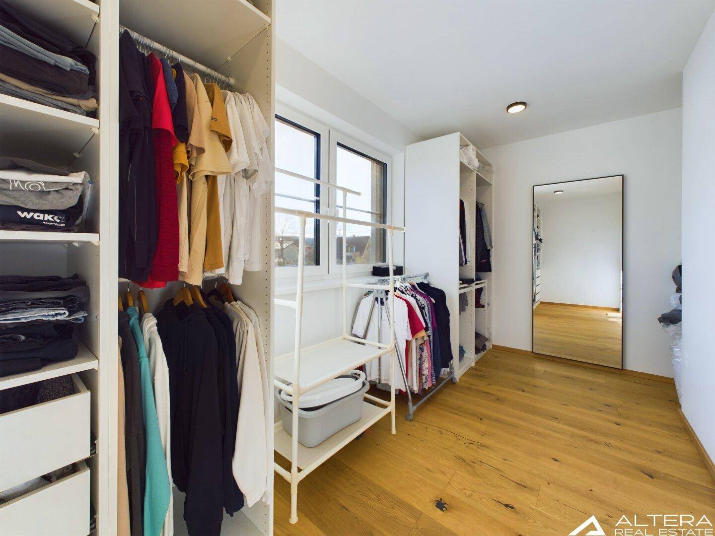 Geräumiges Ankleidezimmer mit Regalen, Kleiderstangen und viel Stauraum für Kleidung.