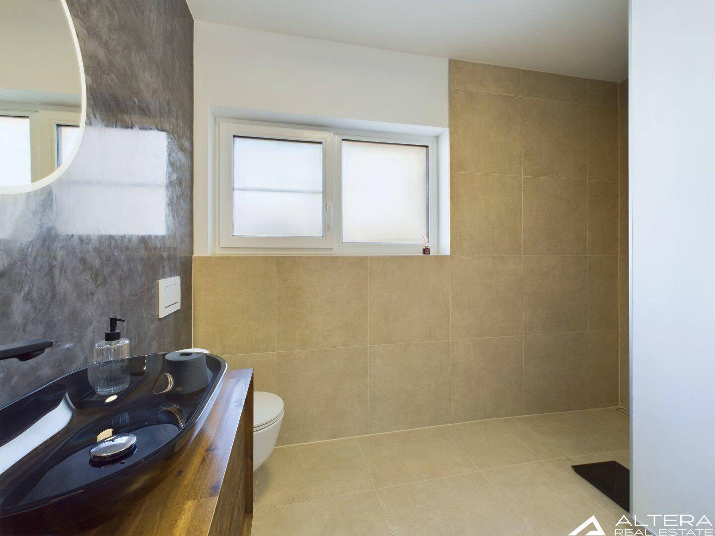 Modernes Badezimmer mit Waschtisch, Toilette und einem Fenster für natürliches Tageslicht.