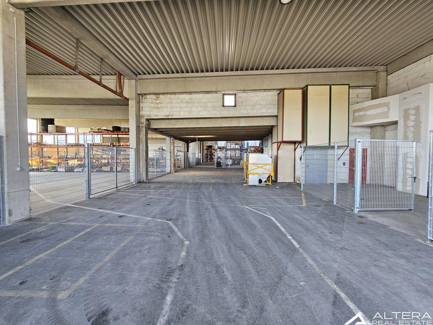 Große Lagerhalle mit mehreren durch Gitterzäune abgetrennten Bereichen und hohen Decken.