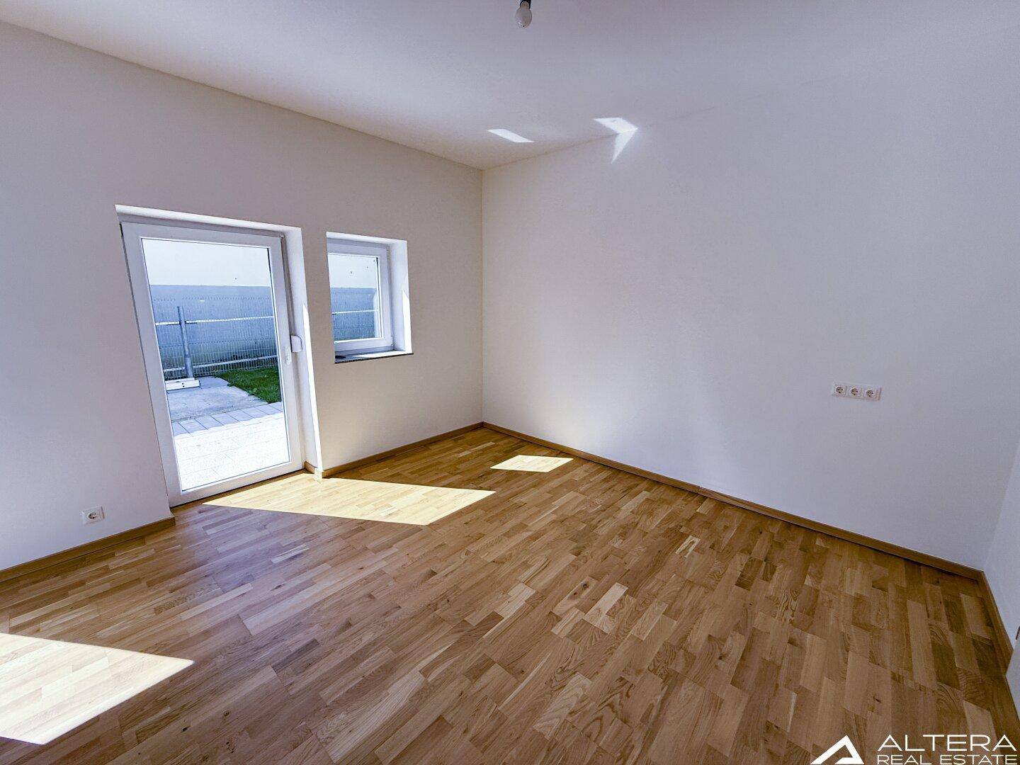Geräumiger, heller Raum mit Parkettboden und Ausgang zur Terrasse, bietet viel Tageslicht.