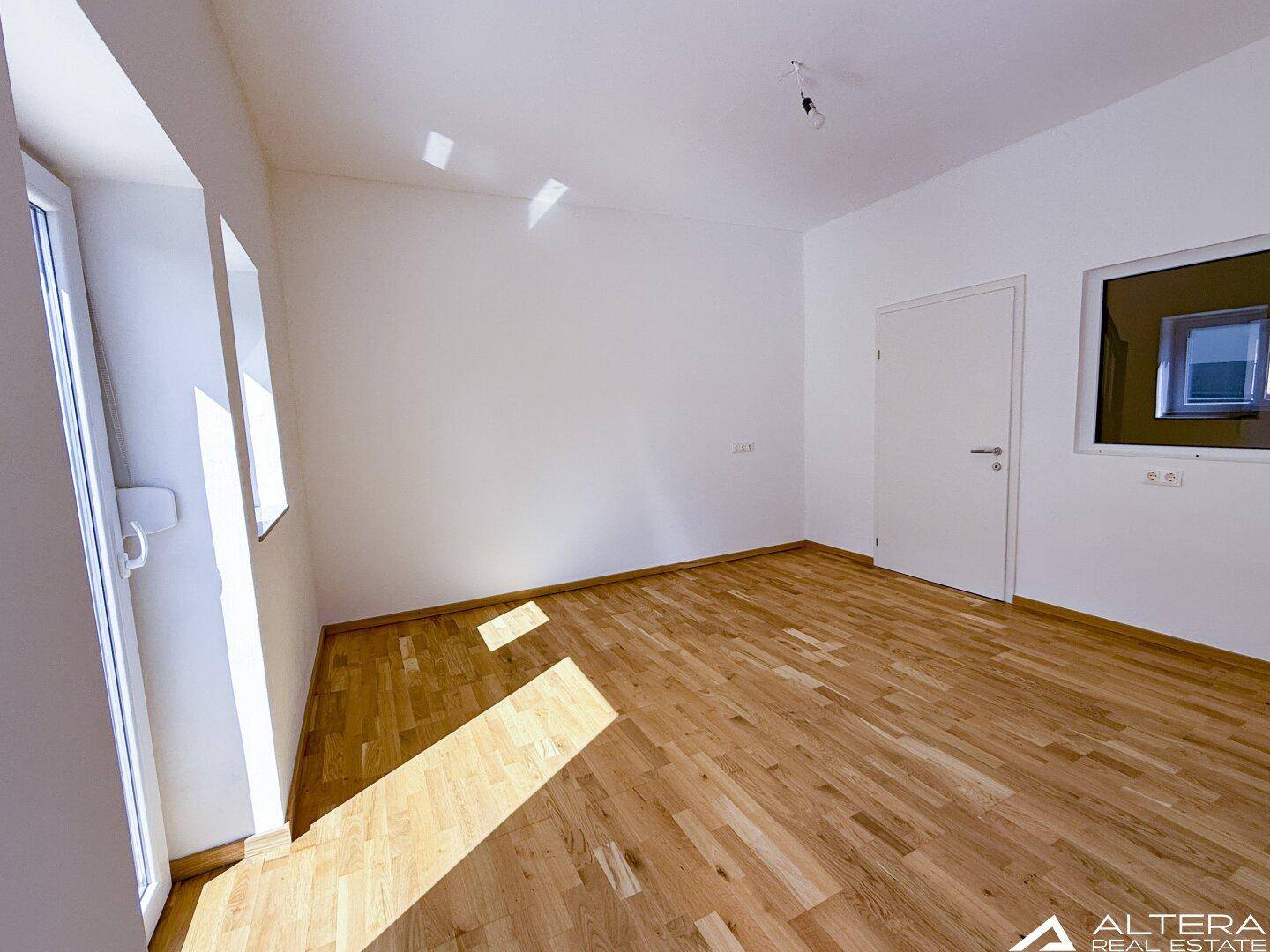 Heller Raum mit Holzboden und weiß gestrichenen Wänden, bietet eine neutrale Basis für Gestaltung.