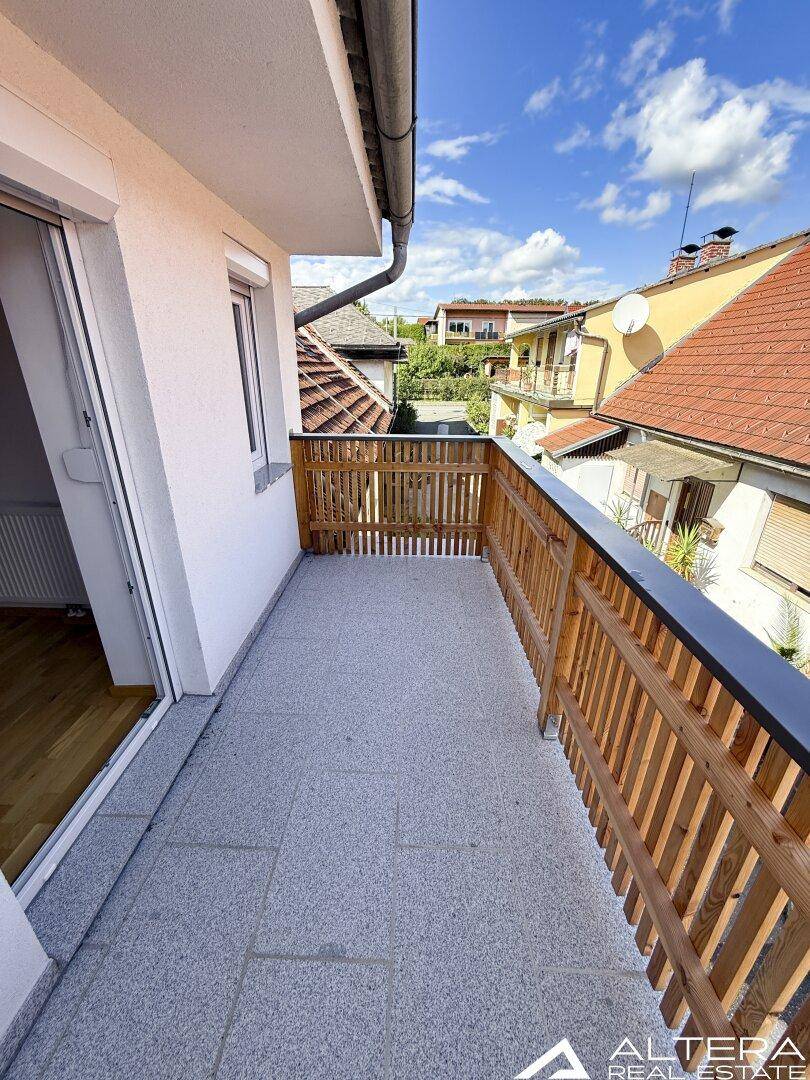 Langer Balkon mit Holzzaun und Fliesenboden, bietet einen schönen Ausblick auf die Umgebung.