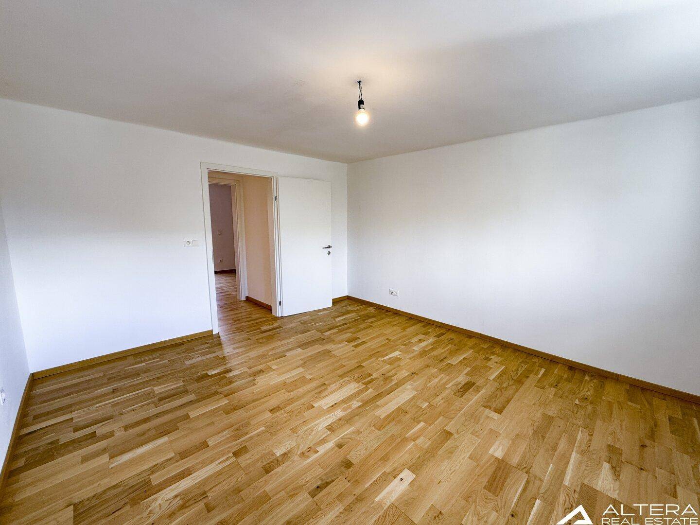 Helles Schlafzimmer mit Parkettboden und weiß gestrichenen Wänden, ideal für Ruhe und Entspannung.