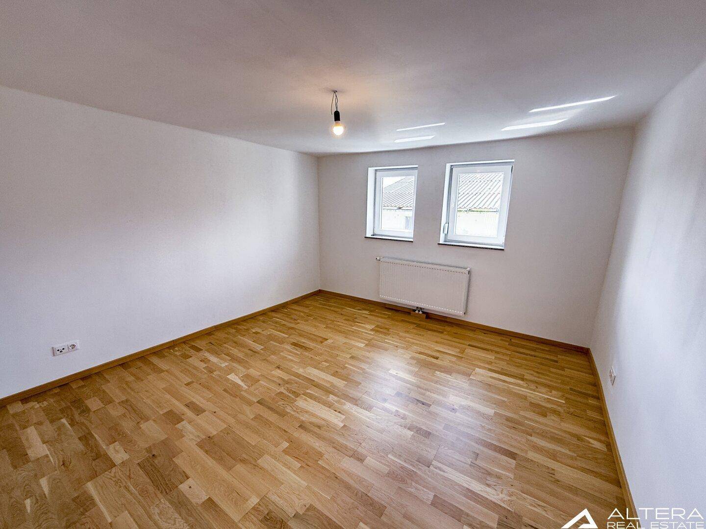 Geräumiges Schlafzimmer mit Parkettboden und Heizkörper, bietet Komfort und viel Tageslicht.