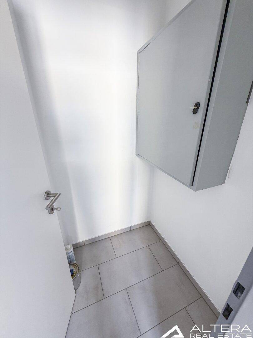 Kleiner Abstellraum mit grauen Fliesen und einem Wandschrank, bietet zusätzlichen Stauraum.