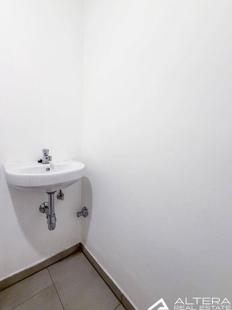 Kleines Waschbecken in einem separaten WC, mit modernen Armaturen und weißen Wänden.