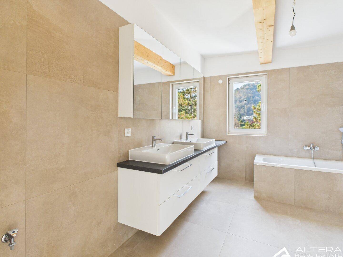 Elegantes Badezimmer mit Doppelwaschbecken, Spiegelschrank, Badewanne und natürlichem Lichteinfall.