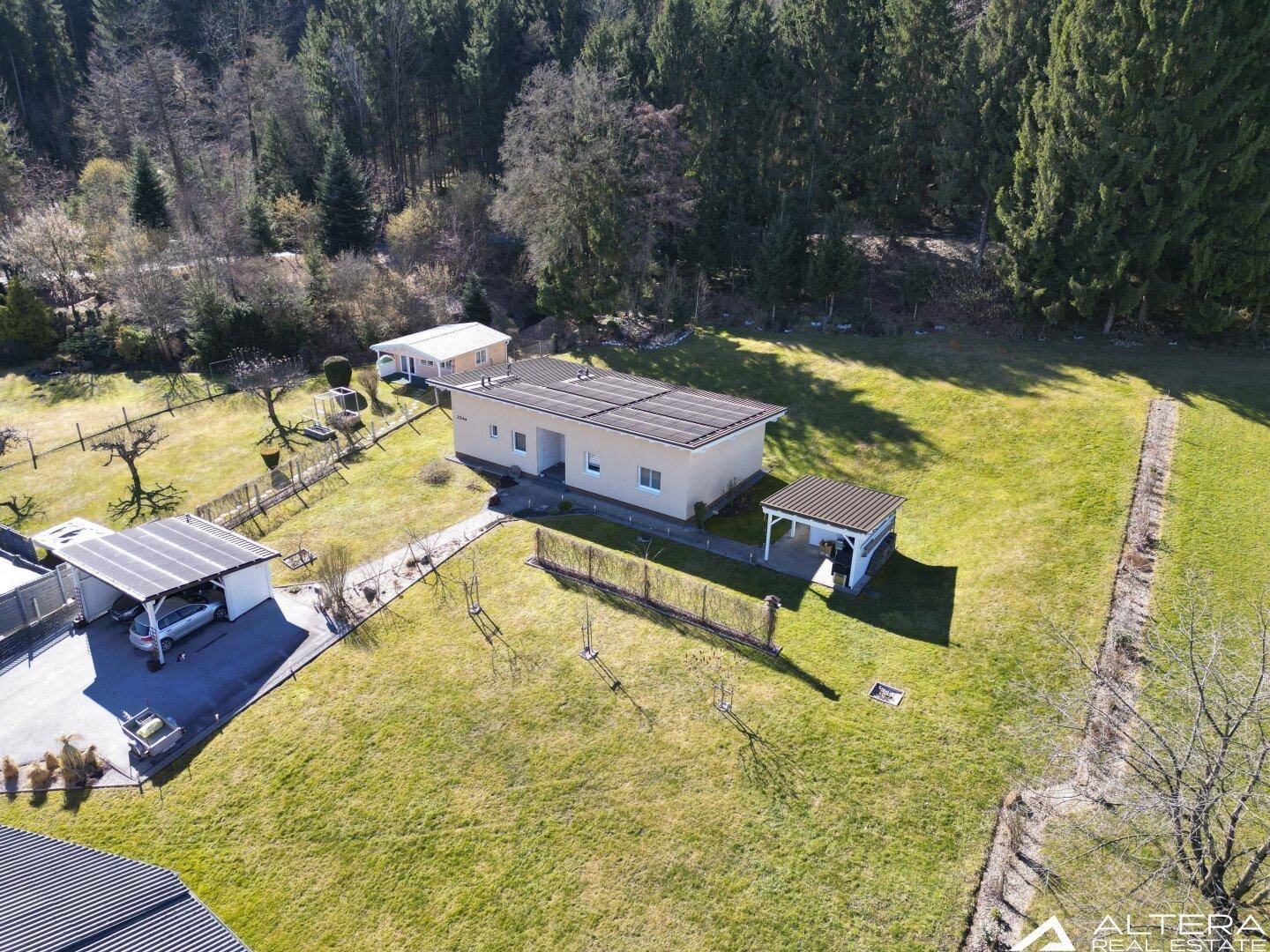 Luftaufnahme eines Einfamilienhauses mit großem Garten und angrenzendem Waldgebiet.