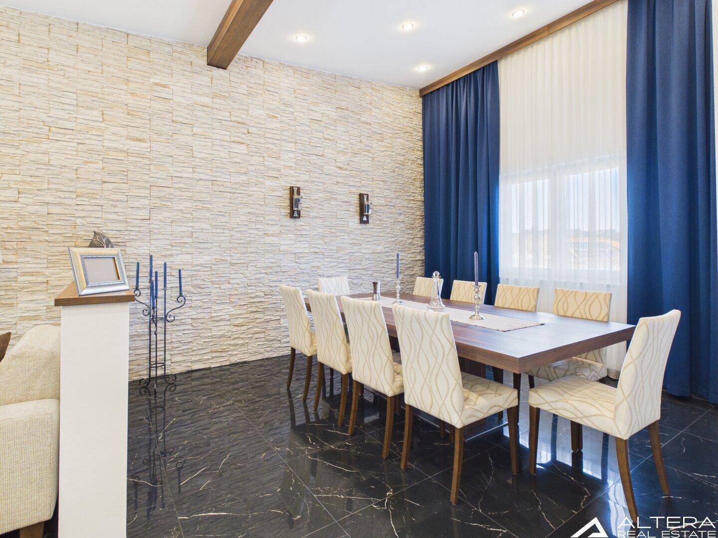 Eleganter Essbereich mit großem Holztisch, bequemen Stühlen und Steinwand.