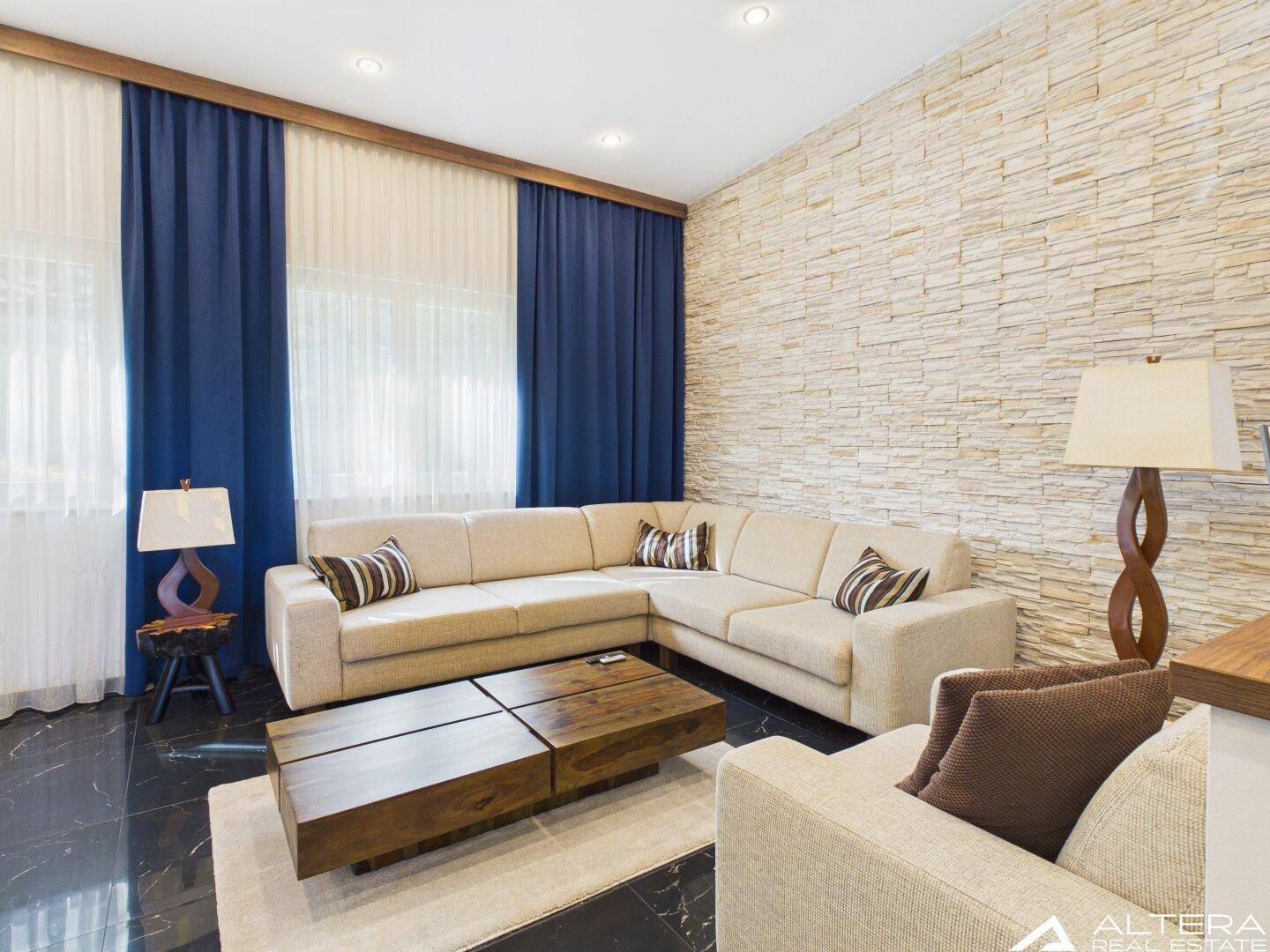 Gemütliches Wohnzimmer mit Ecksofa, Holztisch und dekorativer Steinwand.