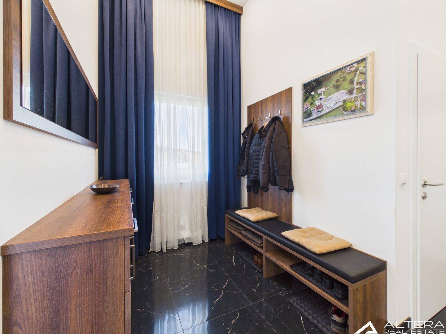 Eingangsbereich mit Garderobe, Sitzbank und großem Spiegel.