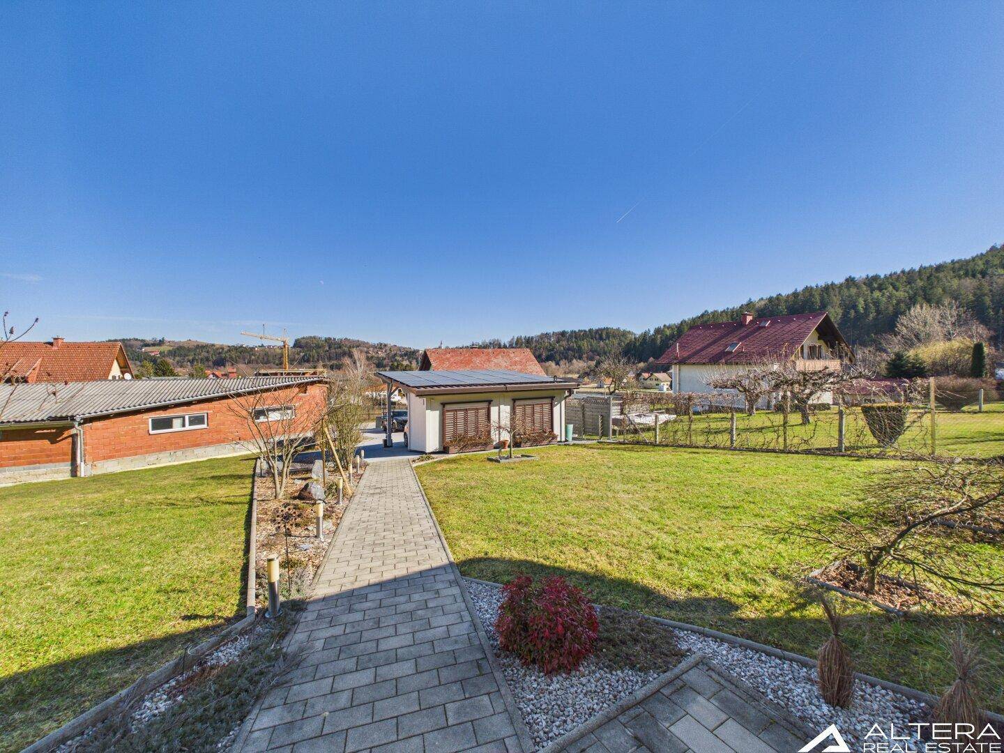 Weitläufiger Gartenbereich mit gepflastertem Weg und Blick auf die Nachbarschaft.
