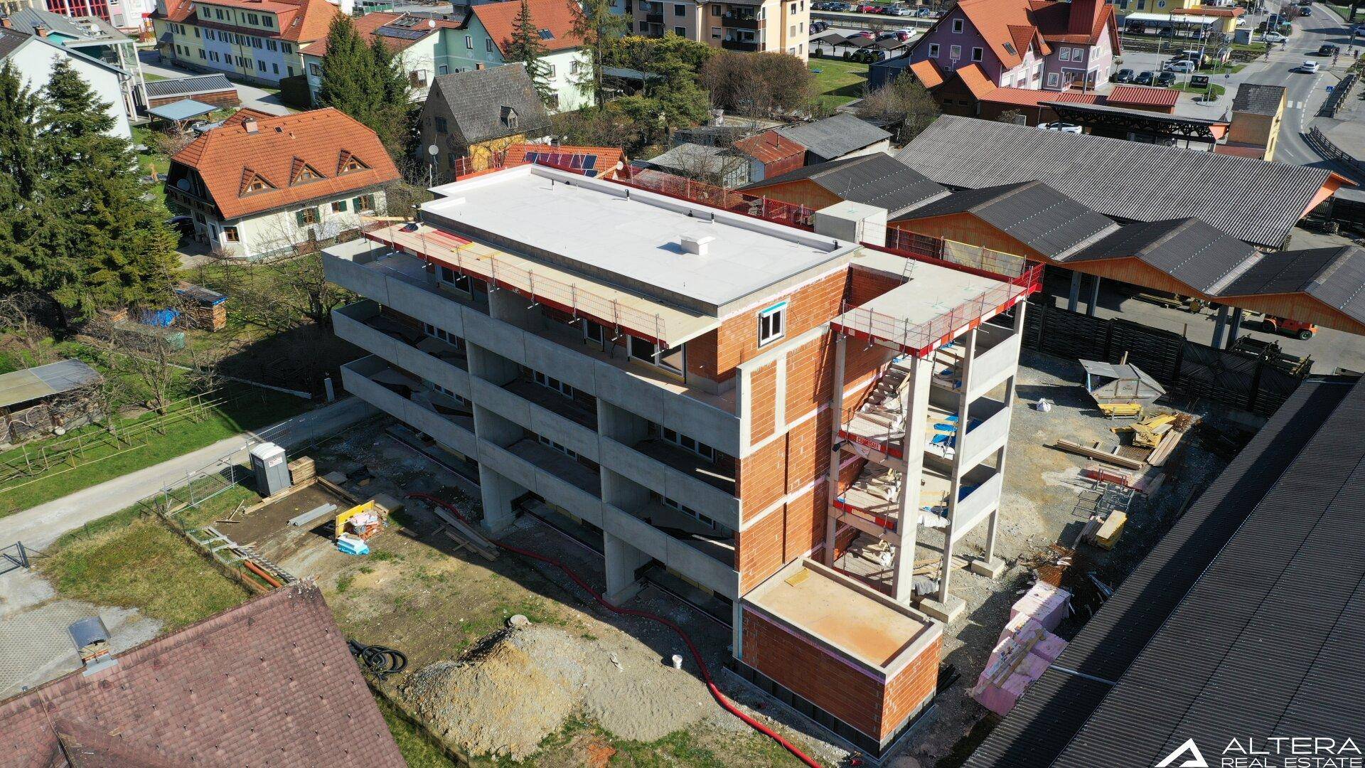 Draufsicht auf ein im Bau befindliches Wohngebäude mit sichtbaren Betonelementen und Dachkonstruktion.