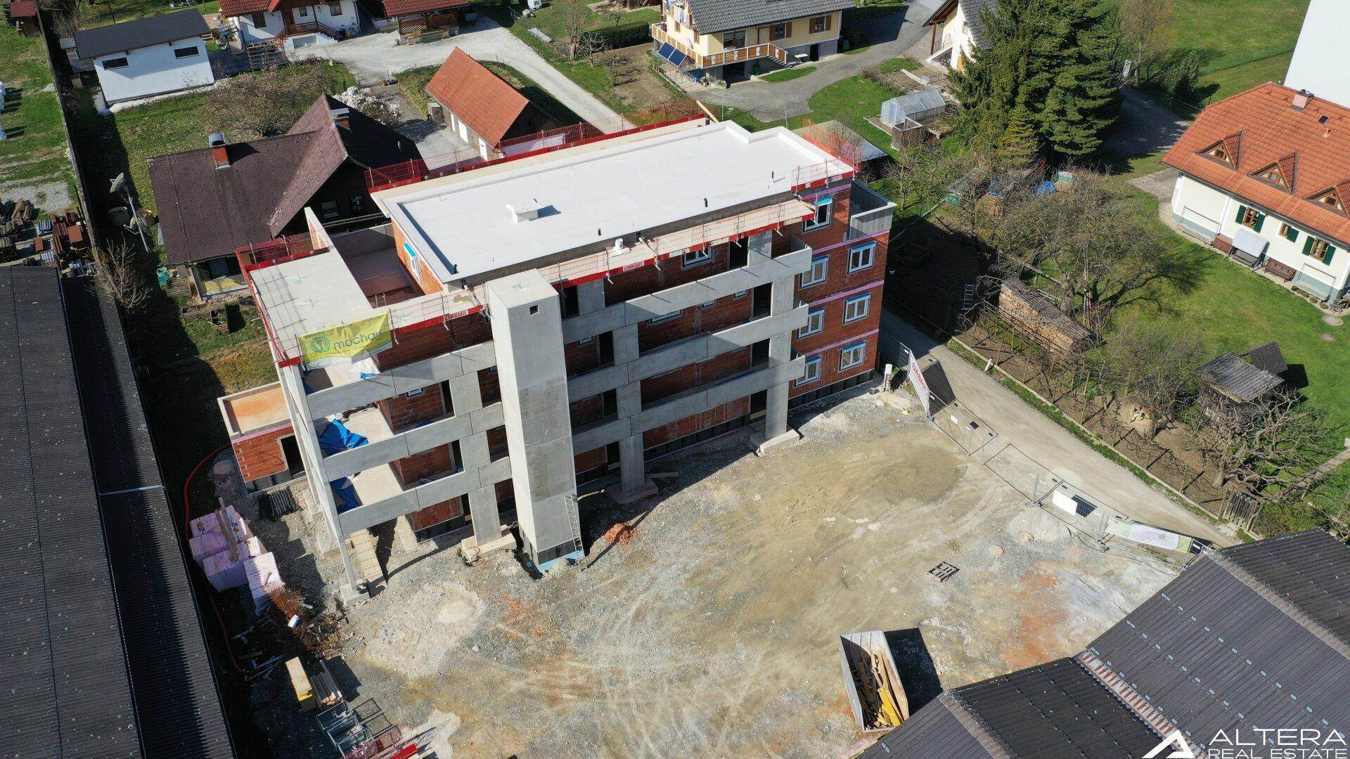 Draufsicht auf das im Bau befindliche Gebäude mit Flachdach und umliegendem Gelände.