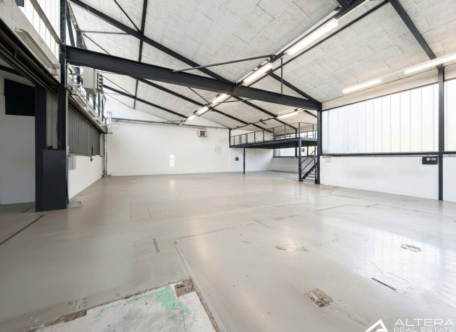 Geräumige Industriehalle mit einer integrierten Stahl-Mezzanine-Ebene und hohen Decken, ideal für zusätzliche Lagerfläche.