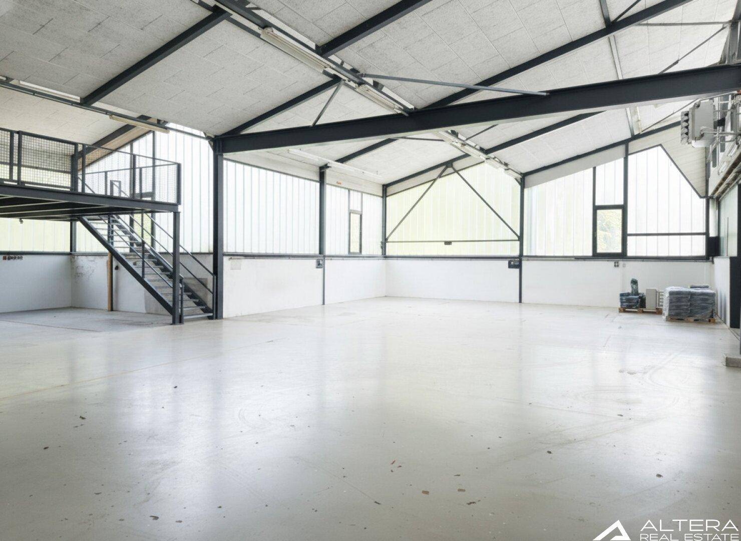 Helle Industriehalle mit einer Mezzanine-Ebene und großen Fenstern, die eine flexible Raumnutzung ermöglicht.