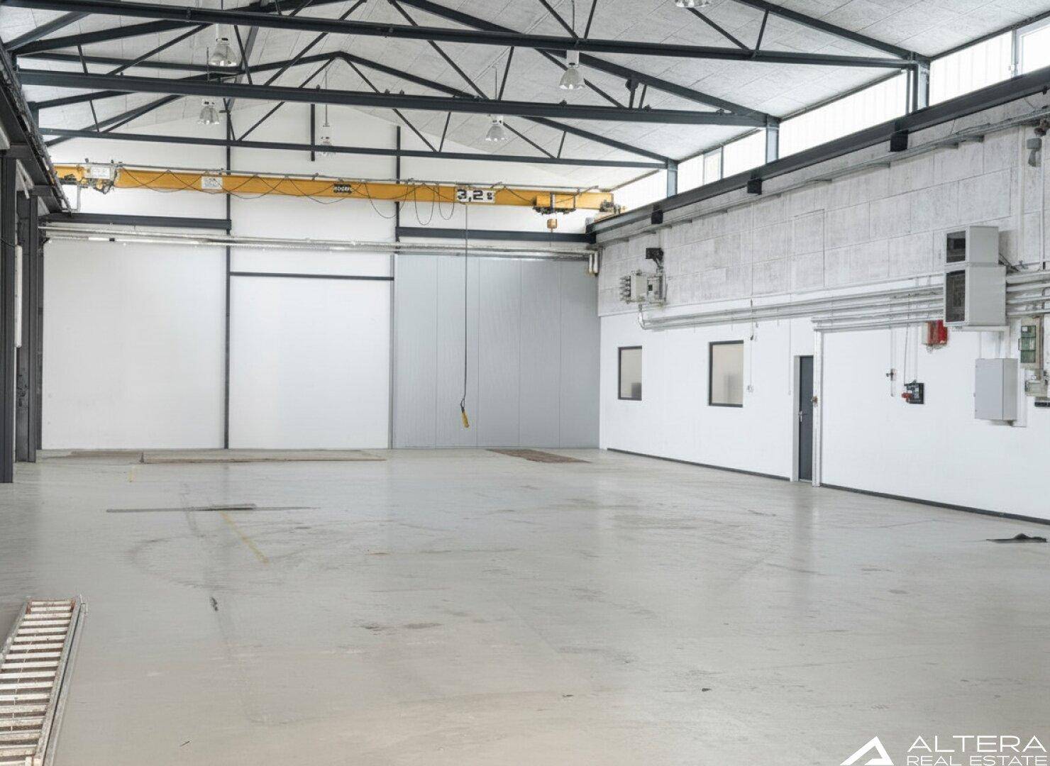 Weitläufige Lagerhalle mit einem 3,2 Tonnen Kran, hohen Decken und großen Fenstern für viel Tageslicht.